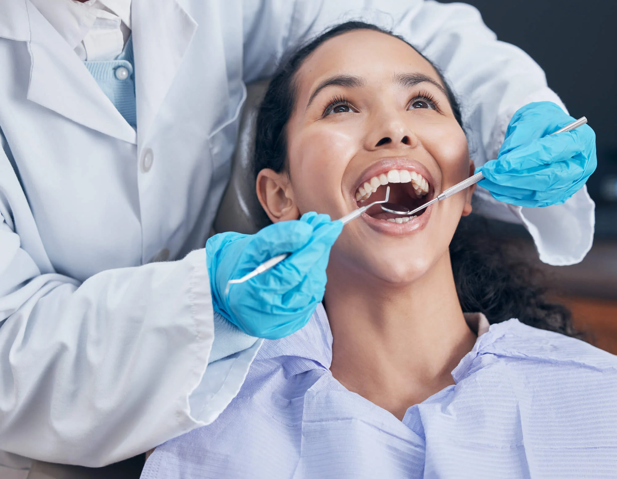 A-dentist-performing-teeth-cleaning-in-Bethesda-MD-on-a-female-patient-in-a-dental-chair