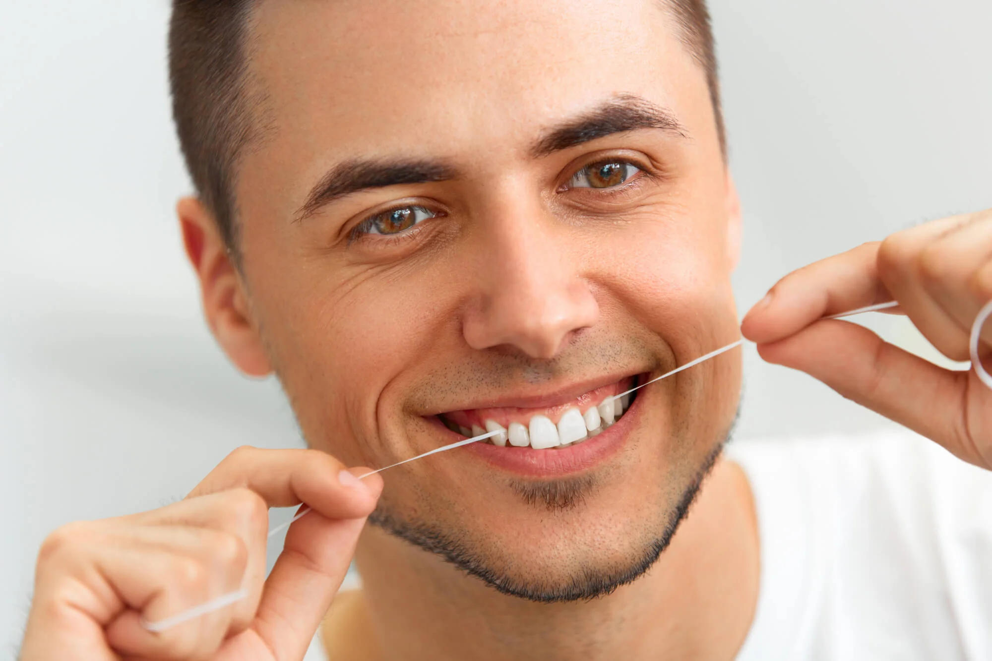 A-young-man-flossing-his-teeth-as-part-of-teeth-cleaning-in-Bethesda-MD