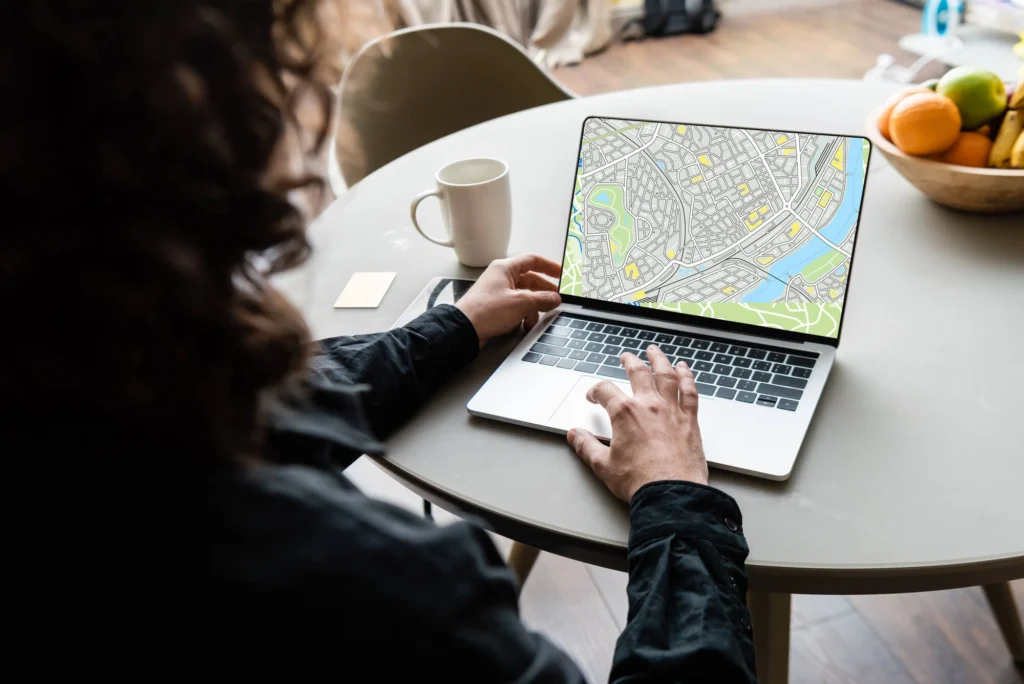 Back view of man using laptop with map on screen to fin a dentist near me